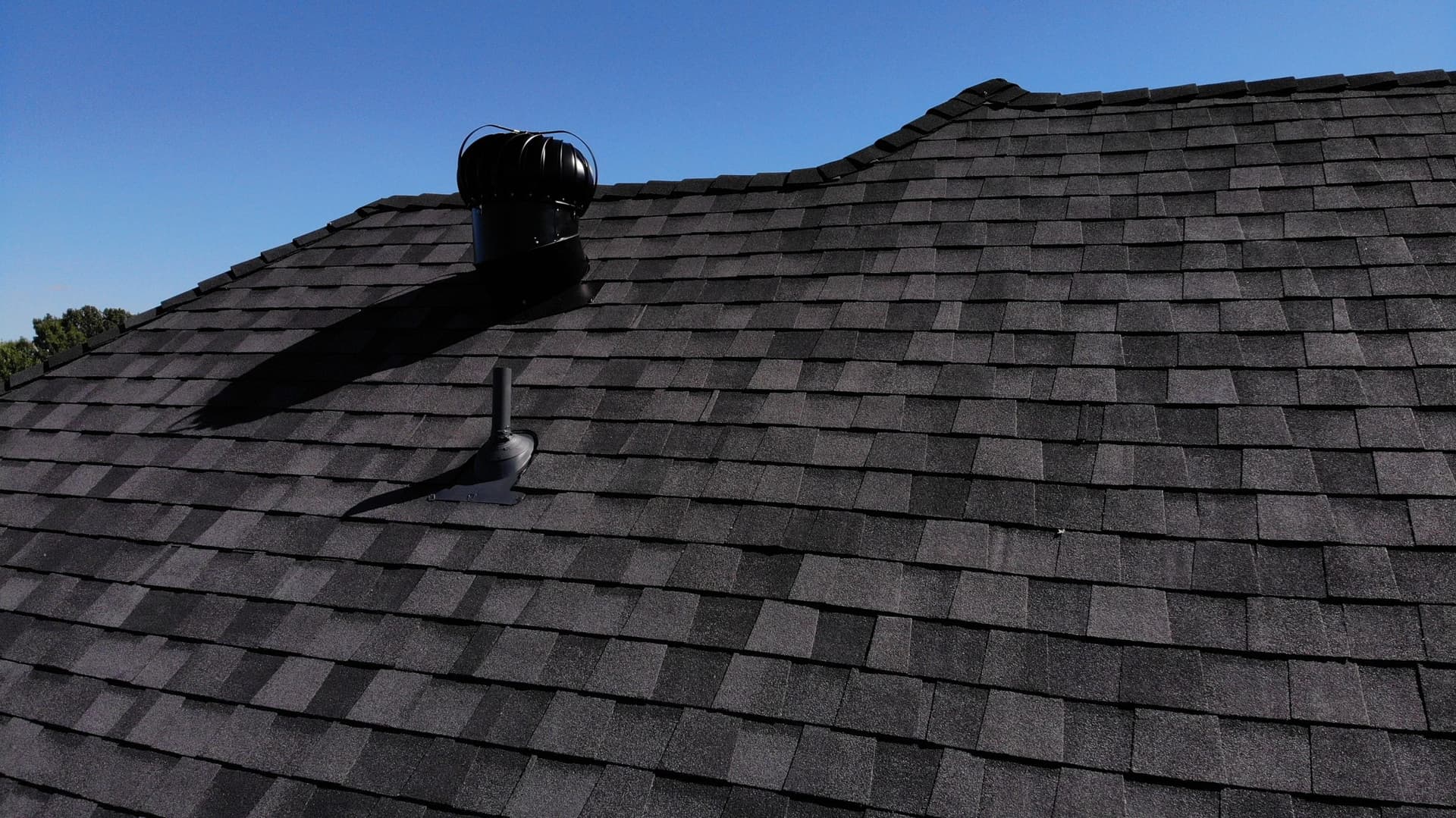 New shingle field and ridge vent detail against a clear sky